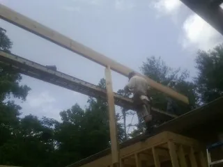 Carpenter setting a ridge beam over a new addition frame — Ice Dam Removal by Roofing Brothers in Malaga